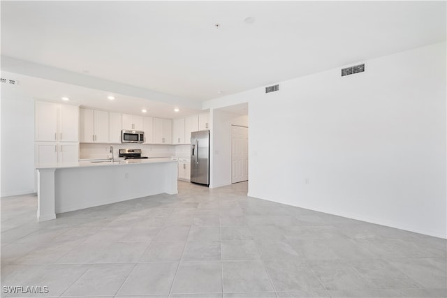 kitchen featuring a kitchen island with sink, white cabinets, sink, light tile patterned flooring, and stainless steel appliances