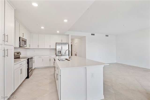 kitchen featuring white cabinets, sink, light tile patterned floors, an island with sink, and appliances with stainless steel finishes