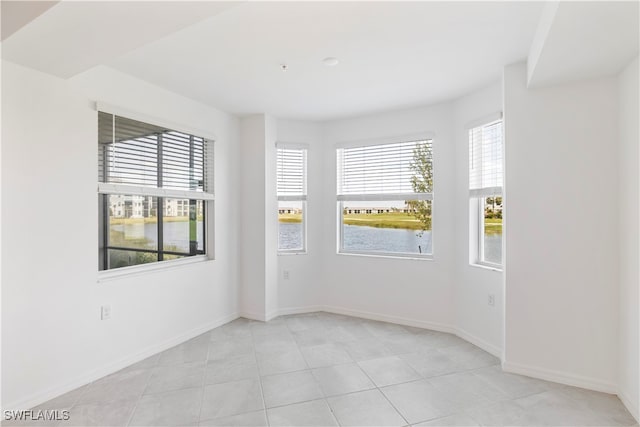 tiled spare room featuring a water view and plenty of natural light