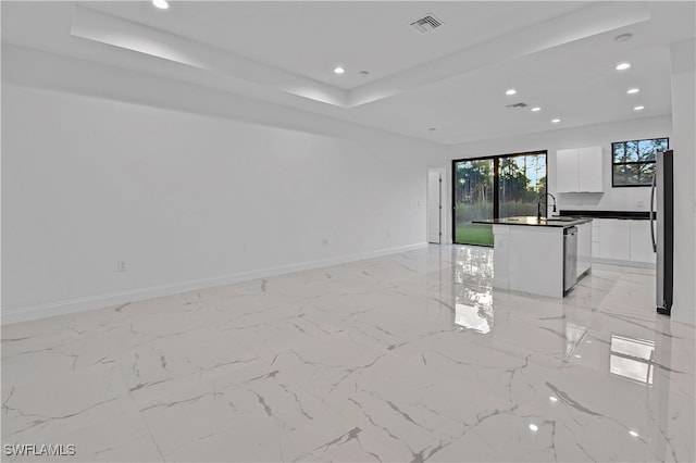 unfurnished living room featuring a raised ceiling and sink