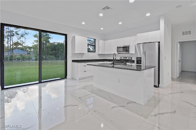 kitchen featuring stainless steel appliances, white cabinetry, a kitchen island with sink, and sink