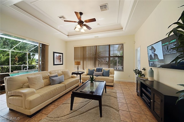 living room with ceiling fan, light tile patterned flooring, and a tray ceiling