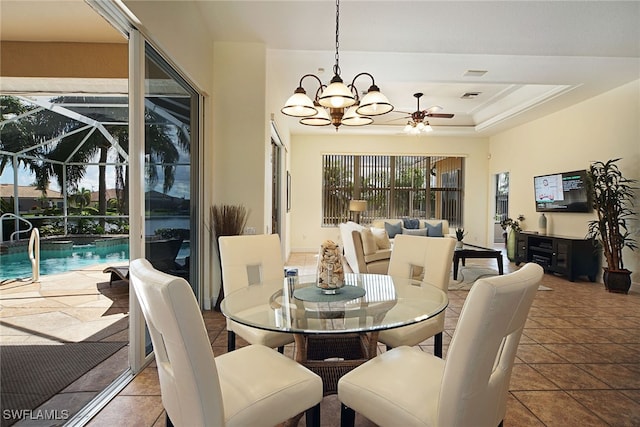 tiled dining space with a raised ceiling and ceiling fan with notable chandelier