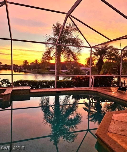 pool at dusk featuring a water view and glass enclosure