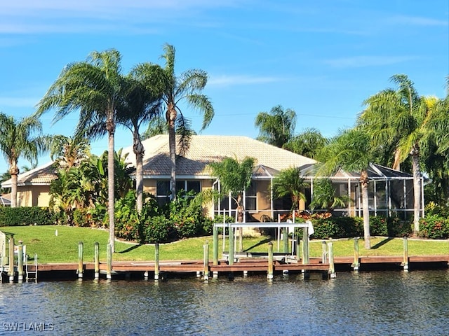 rear view of property with glass enclosure, a lawn, and a water view