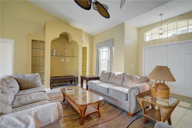 tiled living room featuring ceiling fan, built in features, and high vaulted ceiling