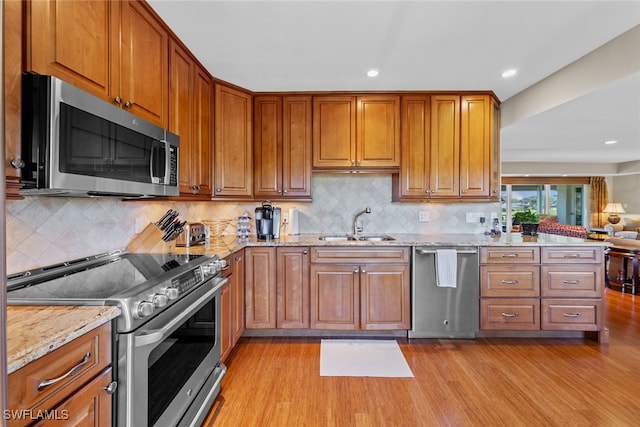 kitchen featuring tasteful backsplash, sink, stainless steel appliances, and light wood-type flooring