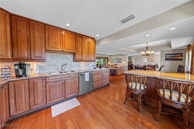 kitchen with backsplash, sink, light hardwood / wood-style flooring, stainless steel dishwasher, and a chandelier