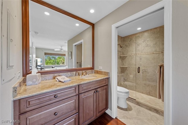 bathroom featuring ceiling fan, walk in shower, tile patterned flooring, toilet, and vanity