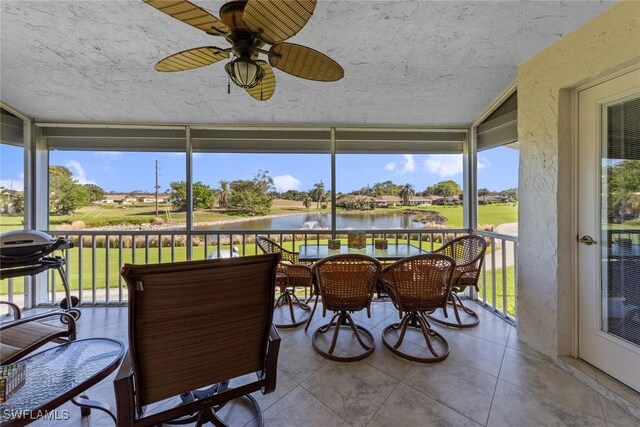 sunroom with a water view and ceiling fan