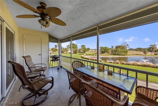 sunroom featuring ceiling fan, a water view, and lofted ceiling