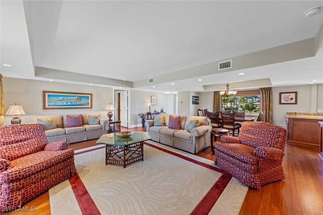 living room featuring light hardwood / wood-style flooring and an inviting chandelier