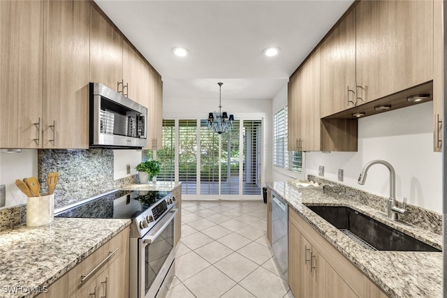 kitchen with light stone countertops, sink, an inviting chandelier, decorative backsplash, and appliances with stainless steel finishes