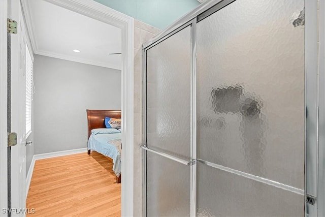 bathroom featuring a shower with shower door, hardwood / wood-style floors, and crown molding