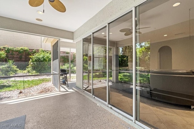 unfurnished sunroom with ceiling fan