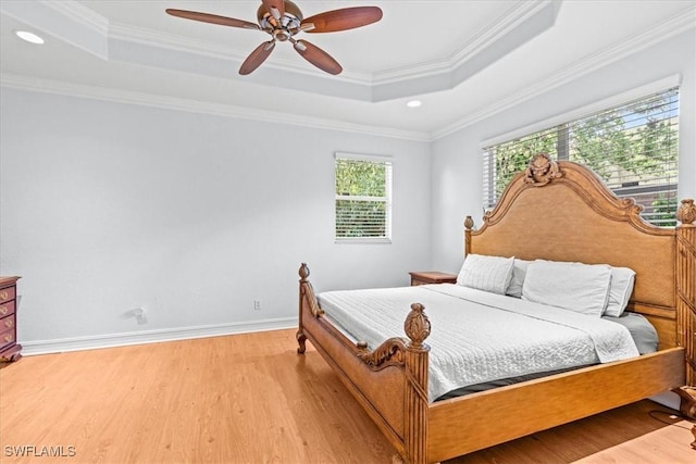 bedroom with a raised ceiling, ceiling fan, light wood-type flooring, and ornamental molding