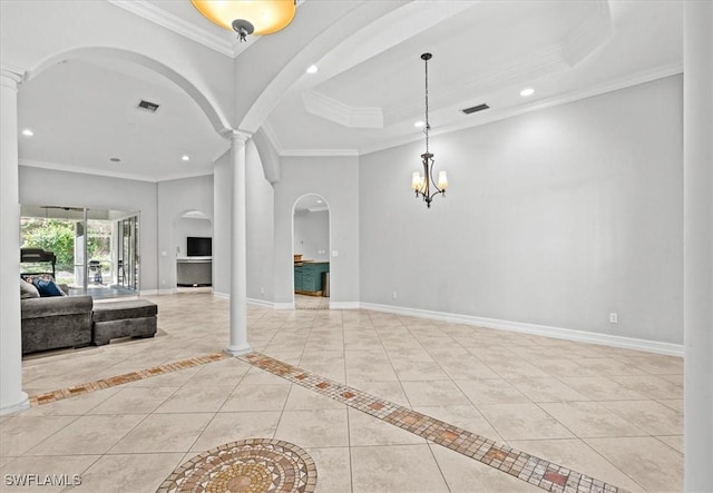 tiled foyer featuring a tray ceiling, ornamental molding, ornate columns, and a chandelier