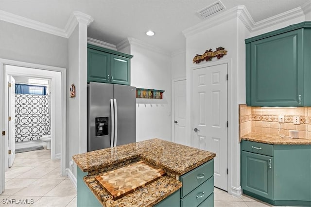 kitchen featuring stainless steel refrigerator with ice dispenser, light stone countertops, green cabinets, and a center island