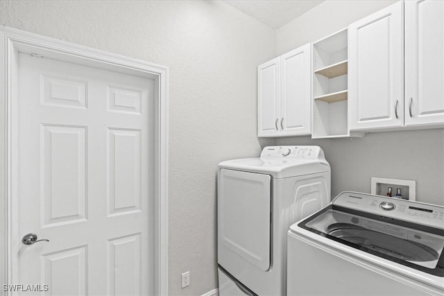 clothes washing area featuring cabinets and washer and clothes dryer