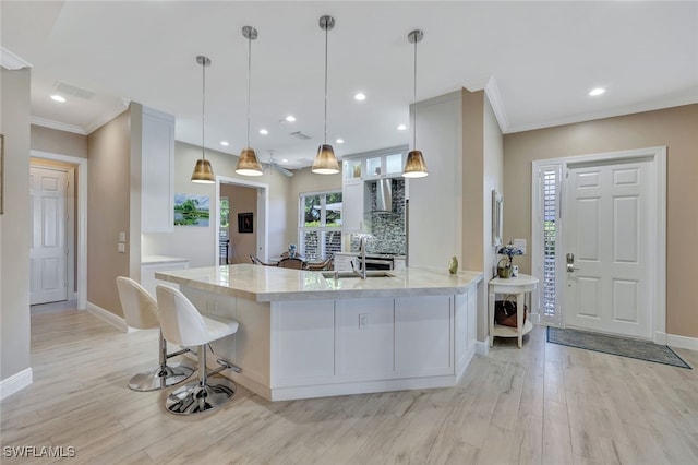 kitchen featuring kitchen peninsula, pendant lighting, white cabinetry, and ornamental molding