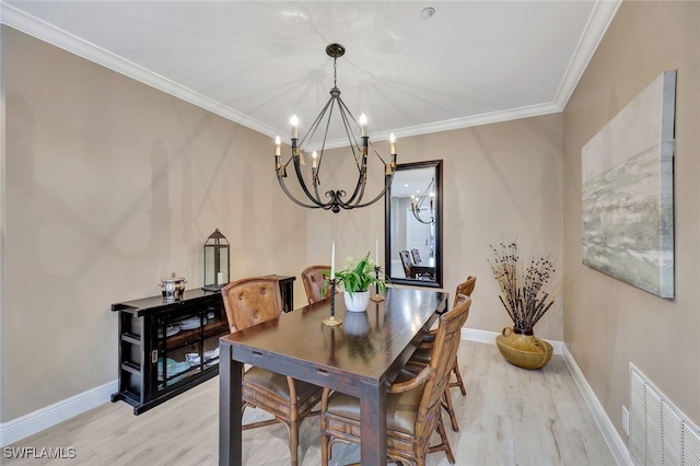 dining space with crown molding, light hardwood / wood-style floors, and an inviting chandelier