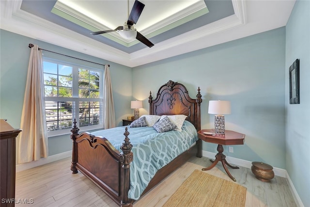 bedroom with ceiling fan, light hardwood / wood-style floors, a raised ceiling, and ornamental molding