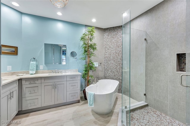 bathroom featuring plus walk in shower, vanity, and tile walls