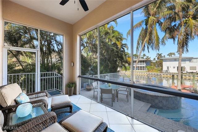 sunroom featuring ceiling fan, plenty of natural light, and a water view