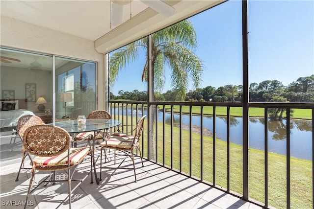 sunroom / solarium featuring a water view and ceiling fan