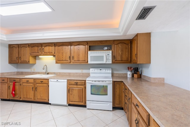 kitchen featuring a tray ceiling, sink, white appliances, and light tile patterned flooring