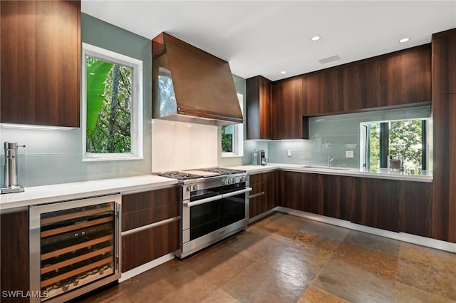 kitchen featuring wine cooler, light countertops, custom range hood, modern cabinets, and double oven range