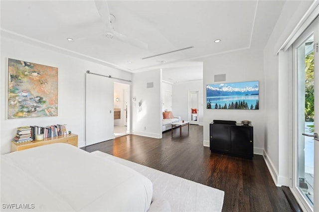 bedroom featuring recessed lighting, wood finished floors, baseboards, and a barn door