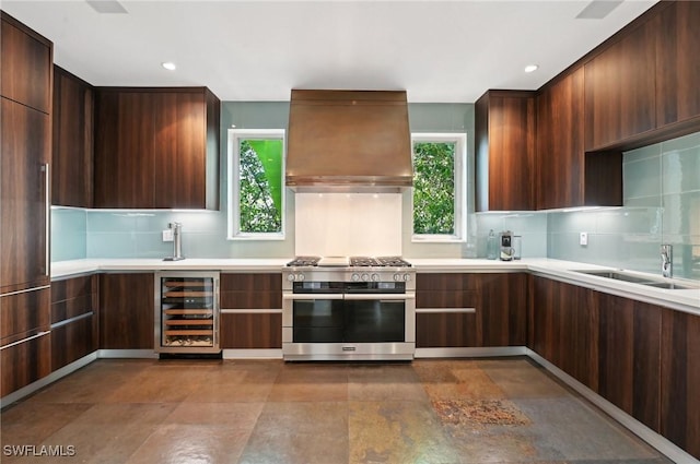 kitchen with range with two ovens, wine cooler, light countertops, ventilation hood, and modern cabinets