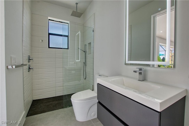 bathroom with tiled shower, tile patterned floors, vanity, and toilet