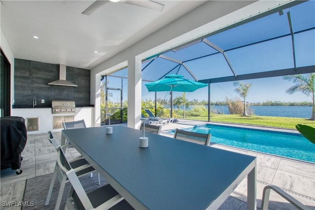 view of pool with area for grilling, exterior kitchen, a water view, glass enclosure, and a patio