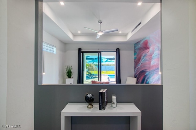 bathroom with ceiling fan and a tray ceiling