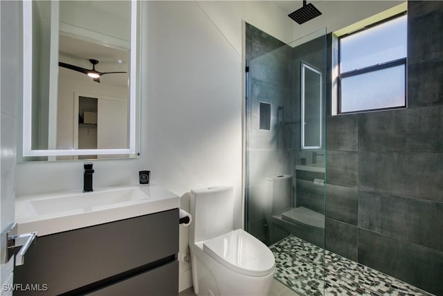 bathroom with ceiling fan, toilet, tiled shower, and vanity