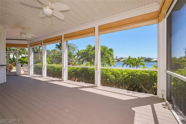 unfurnished sunroom with ceiling fan and a water view