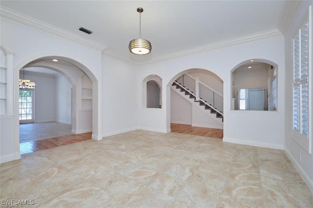 empty room featuring built in shelves, light hardwood / wood-style floors, ornamental molding, and a chandelier