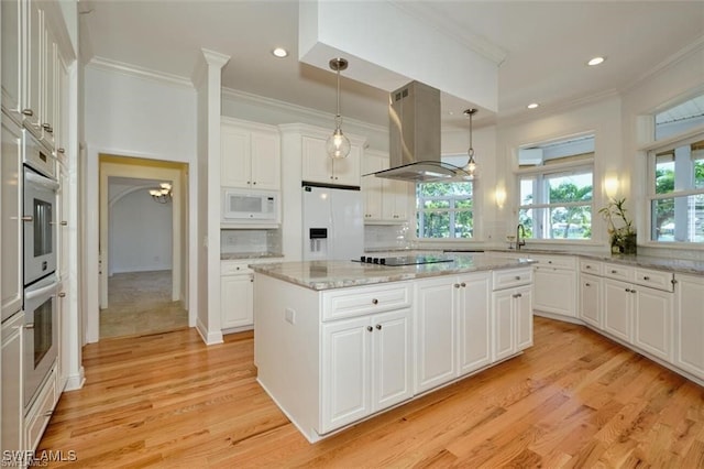 kitchen with a center island, hanging light fixtures, island exhaust hood, white appliances, and white cabinets