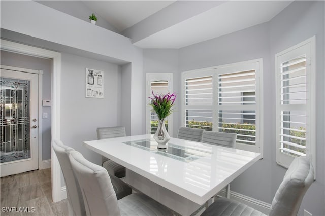 dining room featuring light wood-type flooring and vaulted ceiling