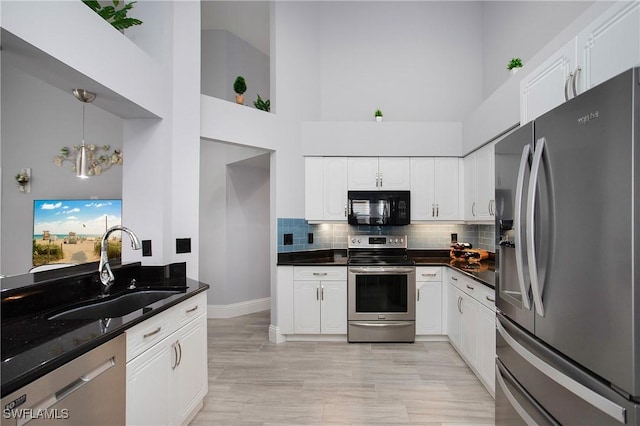 159 Lady Palm Dr, Naples, FL 34104 - kitchen with appliances with stainless steel finishes, a towering ceiling, white cabinets, decorative backsplash, and hanging light fixtures