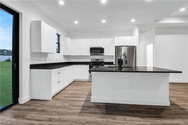 kitchen featuring white cabinets, an island with sink, stainless steel appliances, and light hardwood / wood-style floors