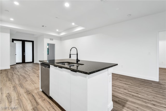 kitchen with white cabinetry, sink, light hardwood / wood-style flooring, stainless steel dishwasher, and a center island with sink