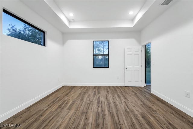 unfurnished room with a tray ceiling and hardwood / wood-style flooring