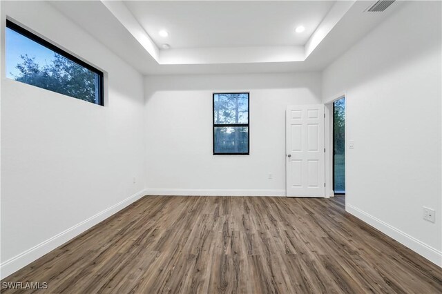 unfurnished room featuring recessed lighting, wood finished floors, visible vents, baseboards, and a raised ceiling