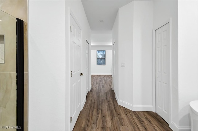 hallway with dark wood finished floors and baseboards