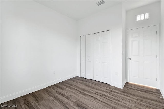 unfurnished bedroom featuring dark hardwood / wood-style flooring and a closet