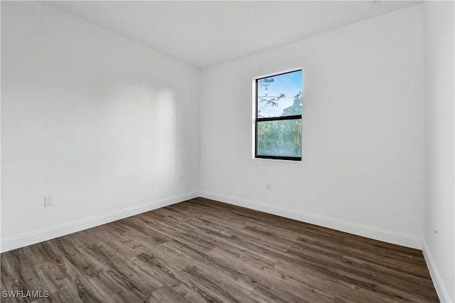 spare room featuring dark wood-type flooring and baseboards