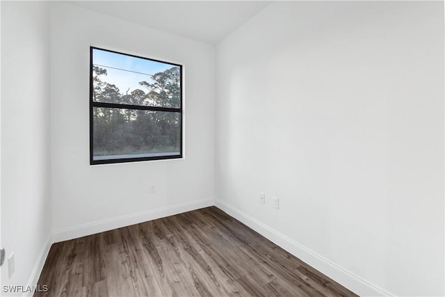 spare room featuring baseboards and wood finished floors